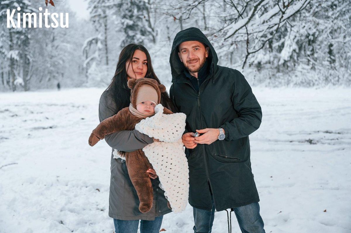 Balade d'hiver avec bébé en porte-bébé physiologique dans un parc enneigé, pour profiter sereinement en famille.