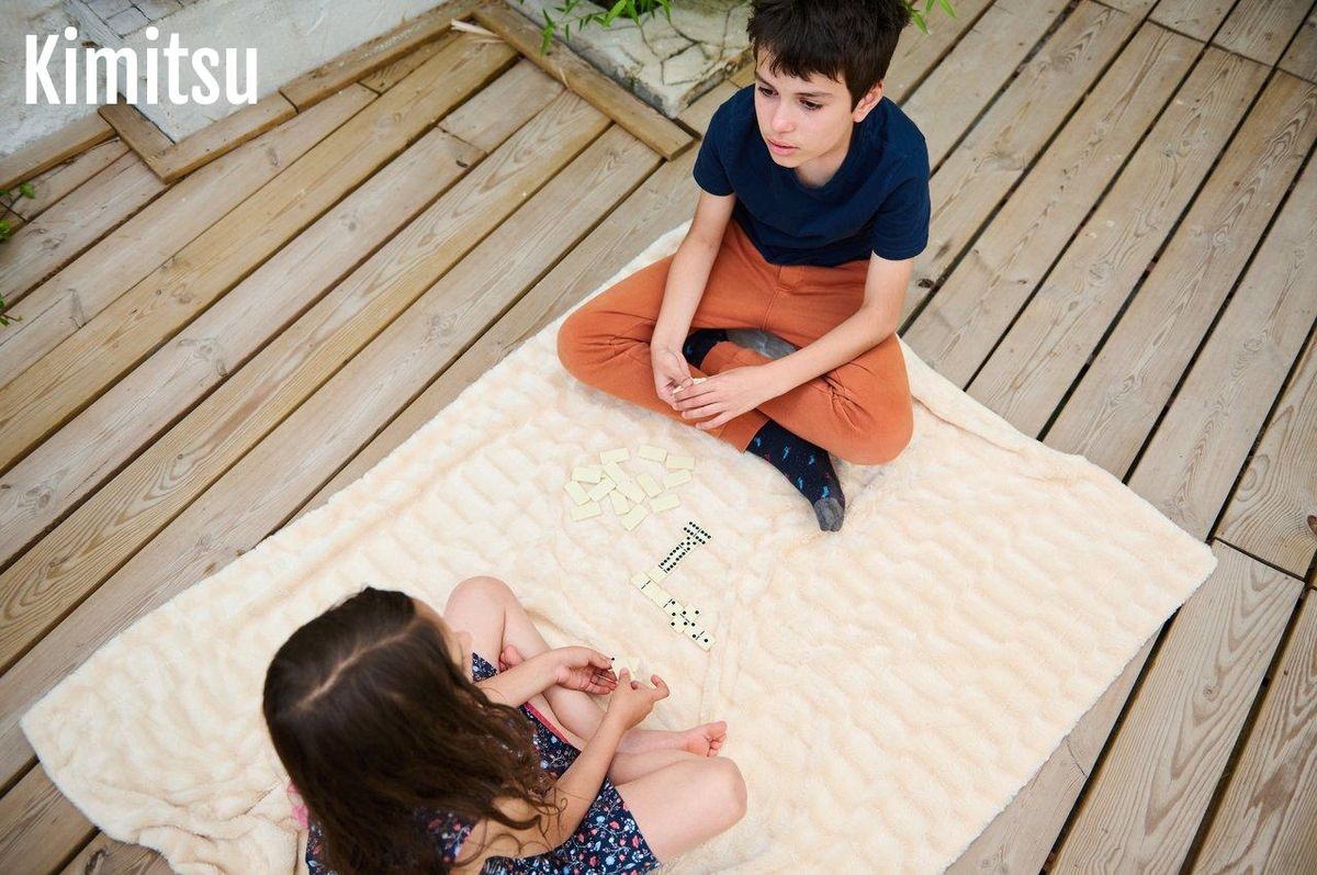 Enfants jouant ensemble à un jeu de société dans un salon lumineux pour renforcer la coopération fraternelle.