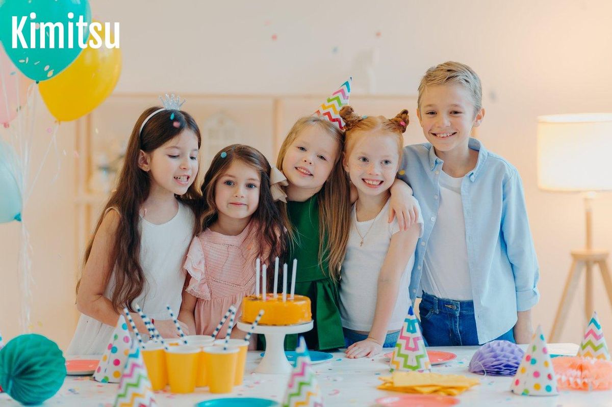 Groupe de enfants joyeux lors d'une birthday party kids, célébrant autour d'un gâteau dans une pièce décorée.
