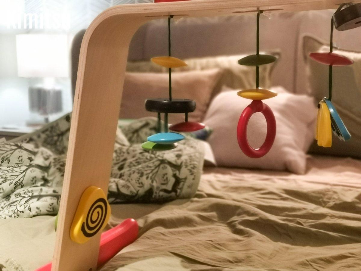 Mobile musical en matériaux naturels suspendu près d’une fenêtre, avec éléments en bois, feutrine et clochettes.