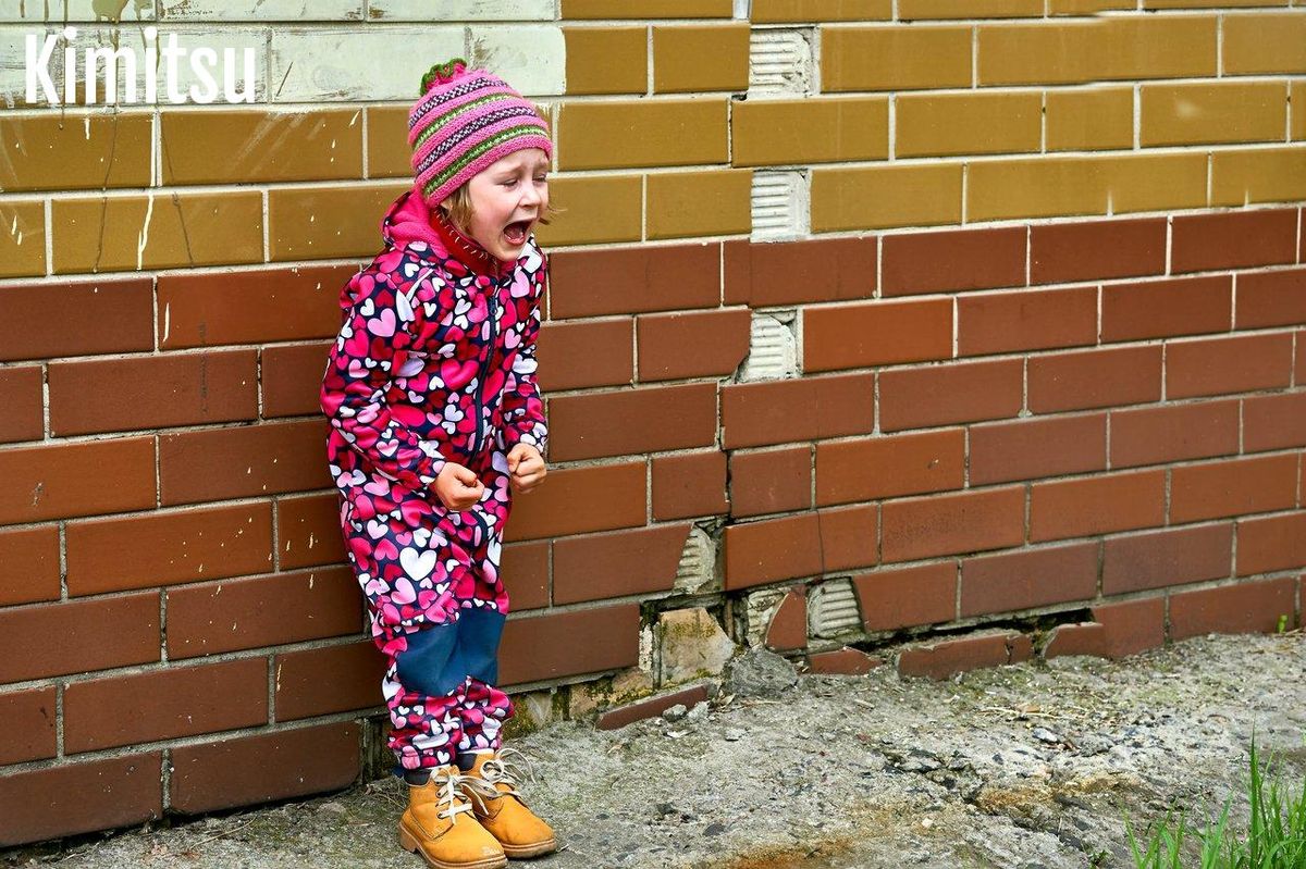 Un enfant choisissant des vêtements sur une tringle basse dans une chambre lumineuse favorise son autonomie.