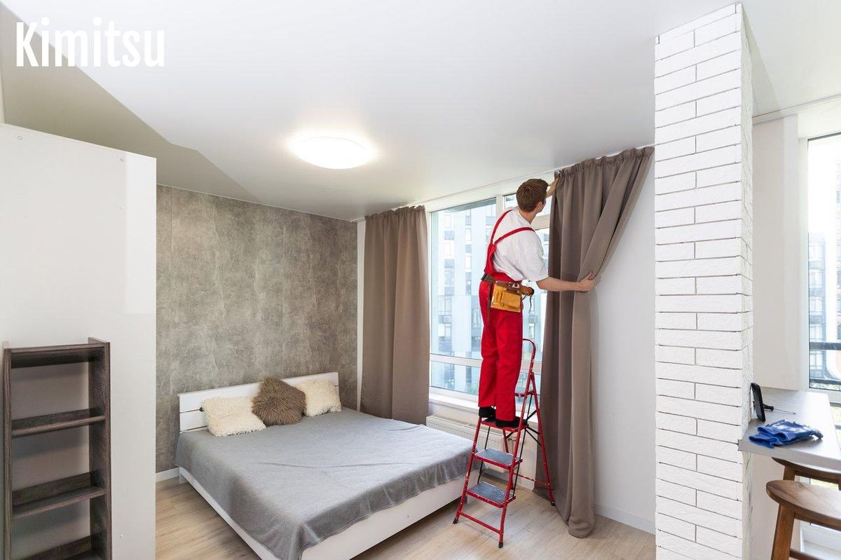 Un expert ajuste des rideaux, clé de l'ambiance et du confort d'une chambre moderne.