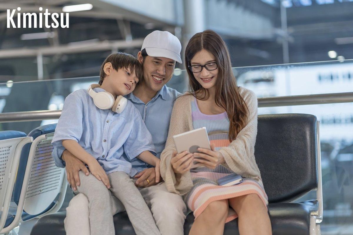 Une famille souriante planifie son voyage à l’étranger sur tablette, illustrant la préparation d’un premier voyage en famille.
