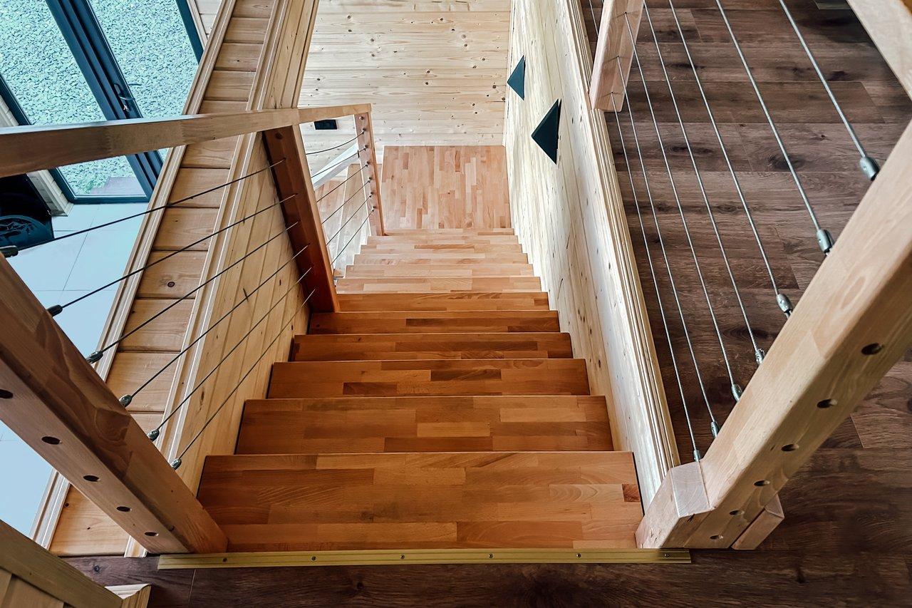 Coin lecture cosy sous escalier avec banquette basse éclairée par LED dimmables, idéal pour un espace de détente chaleureux.