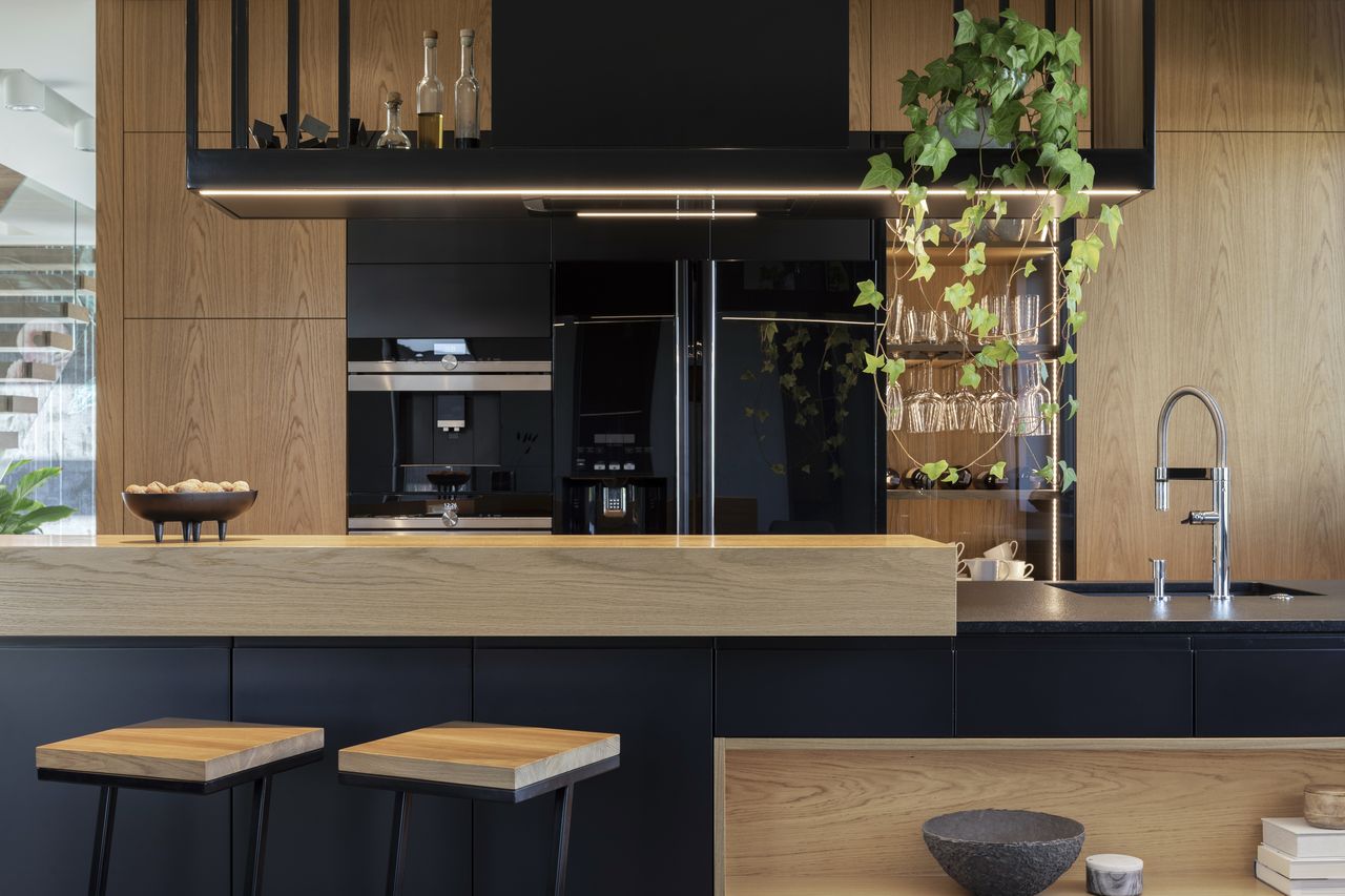 Cuisine 2026 minimaliste en bois clair et pierre mate, avec îlot arrondi et appareils connectés.