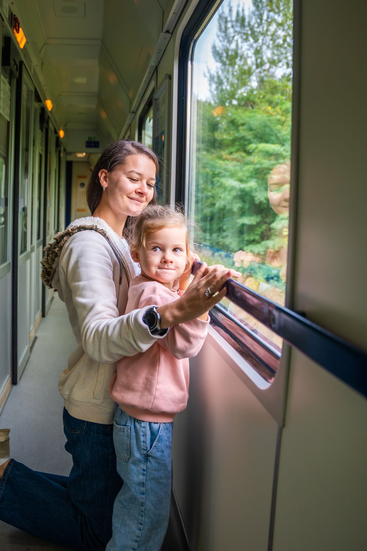 Famille avec enfants voyageant en train, sacs légers, ambiance douce et apaisée au fil du trajet.
