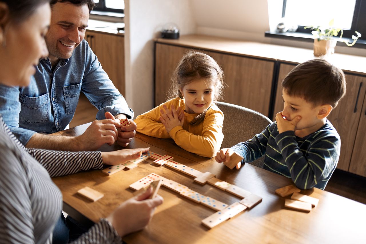Famille heureuse jouant à un jeu de société coopératif dans le salon à la maison