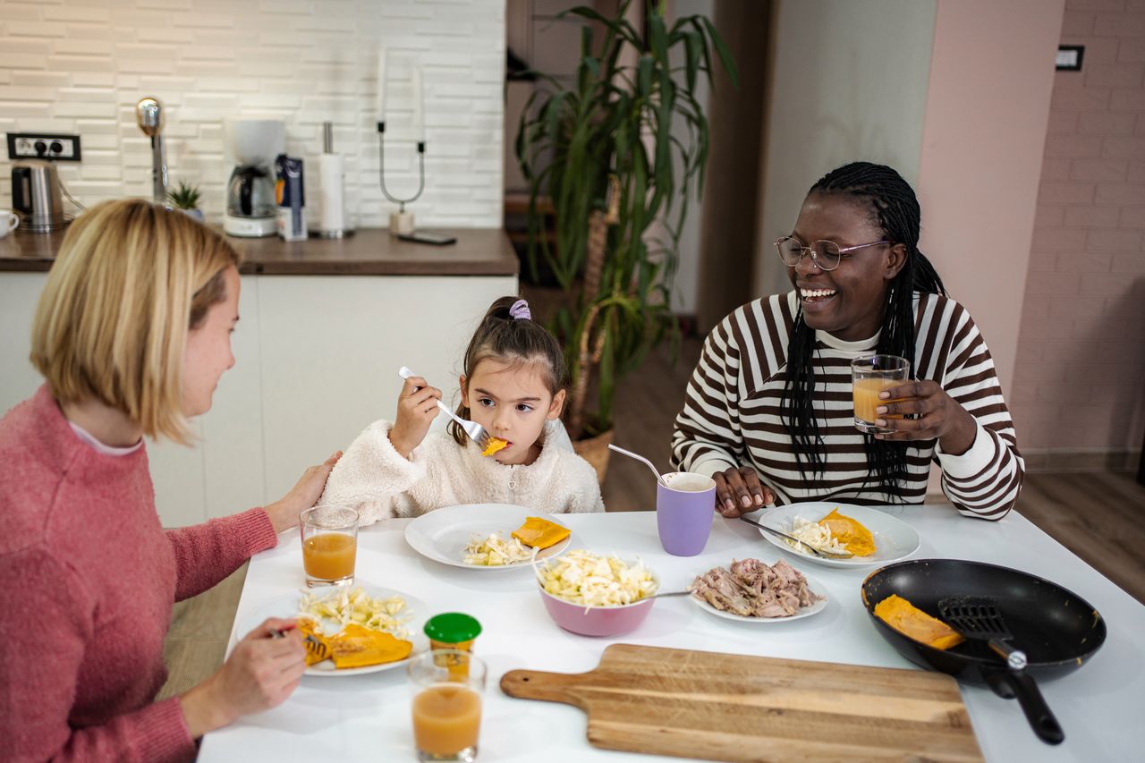 Famille multiraciale partageant un dîner économique et coloré à la maison pour la rentrée.