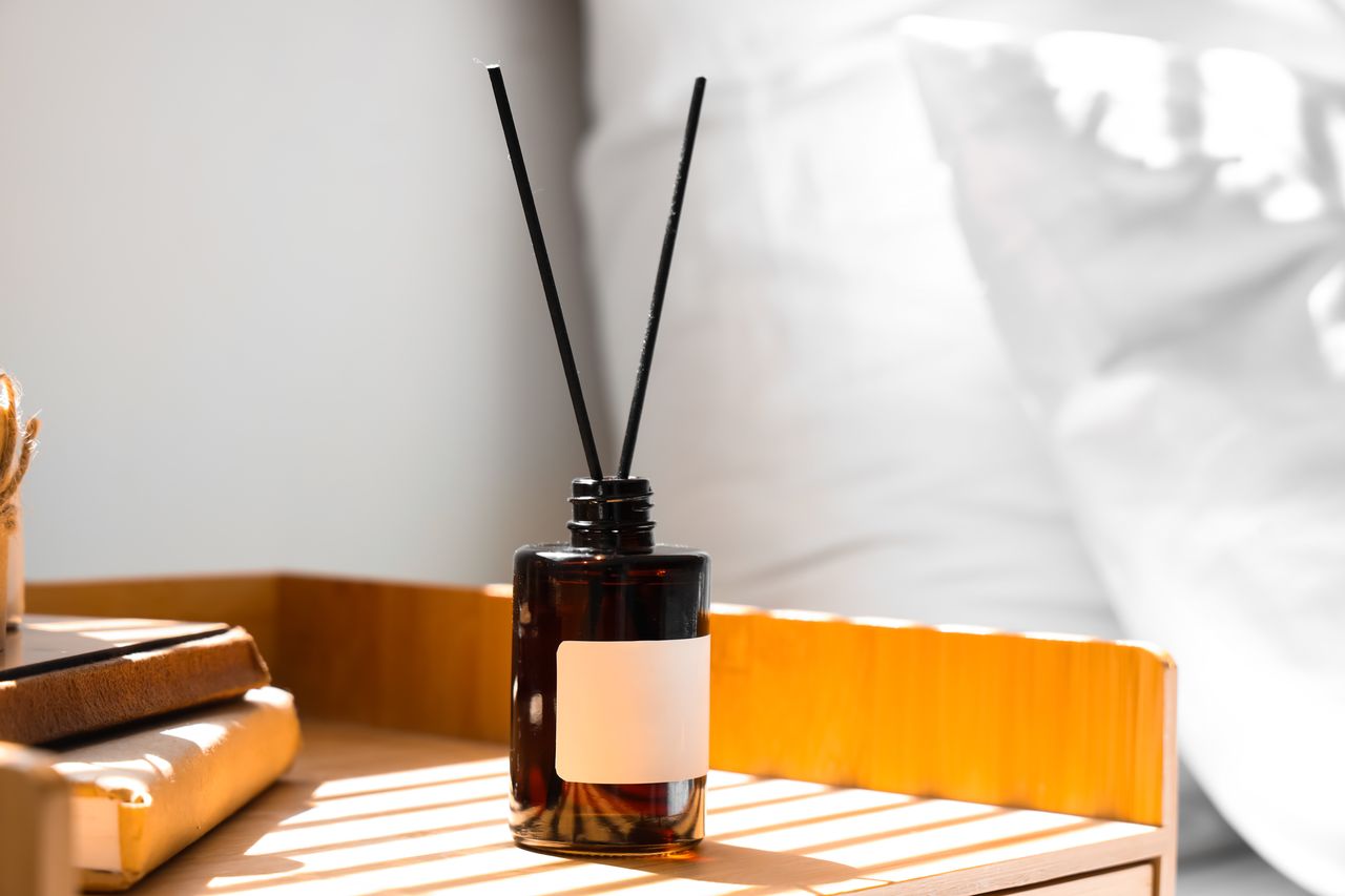 Flacon d’huiles essentielles et diffuseur sur table de chevet, ambiance nuit douce et apaisante.