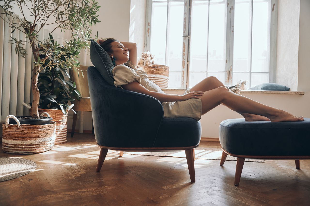 Jeune femme en micro-sieste sur un fauteuil confortable dans un intérieur lumineux et paisible.