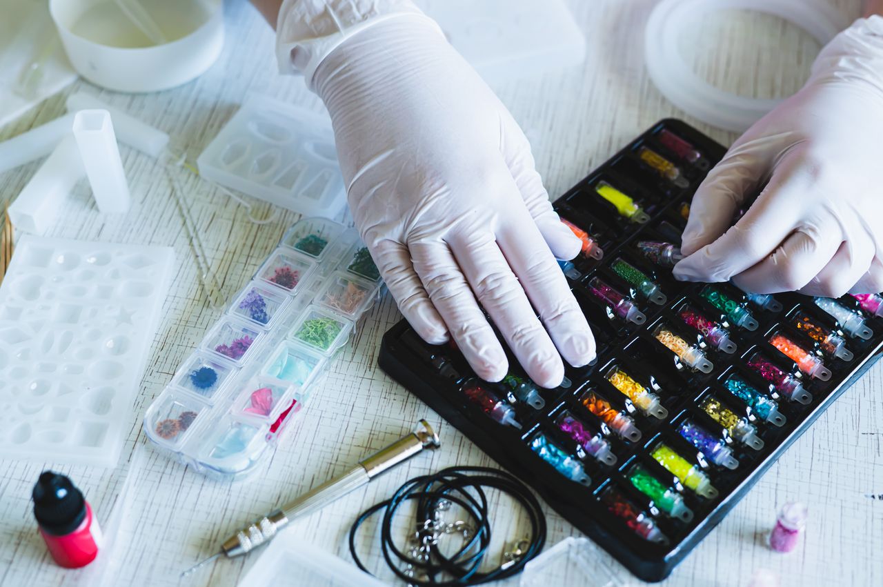 Kit débutant pour bijoux en résine époxy avec moules, pigments, gants et décorations scintillantes.