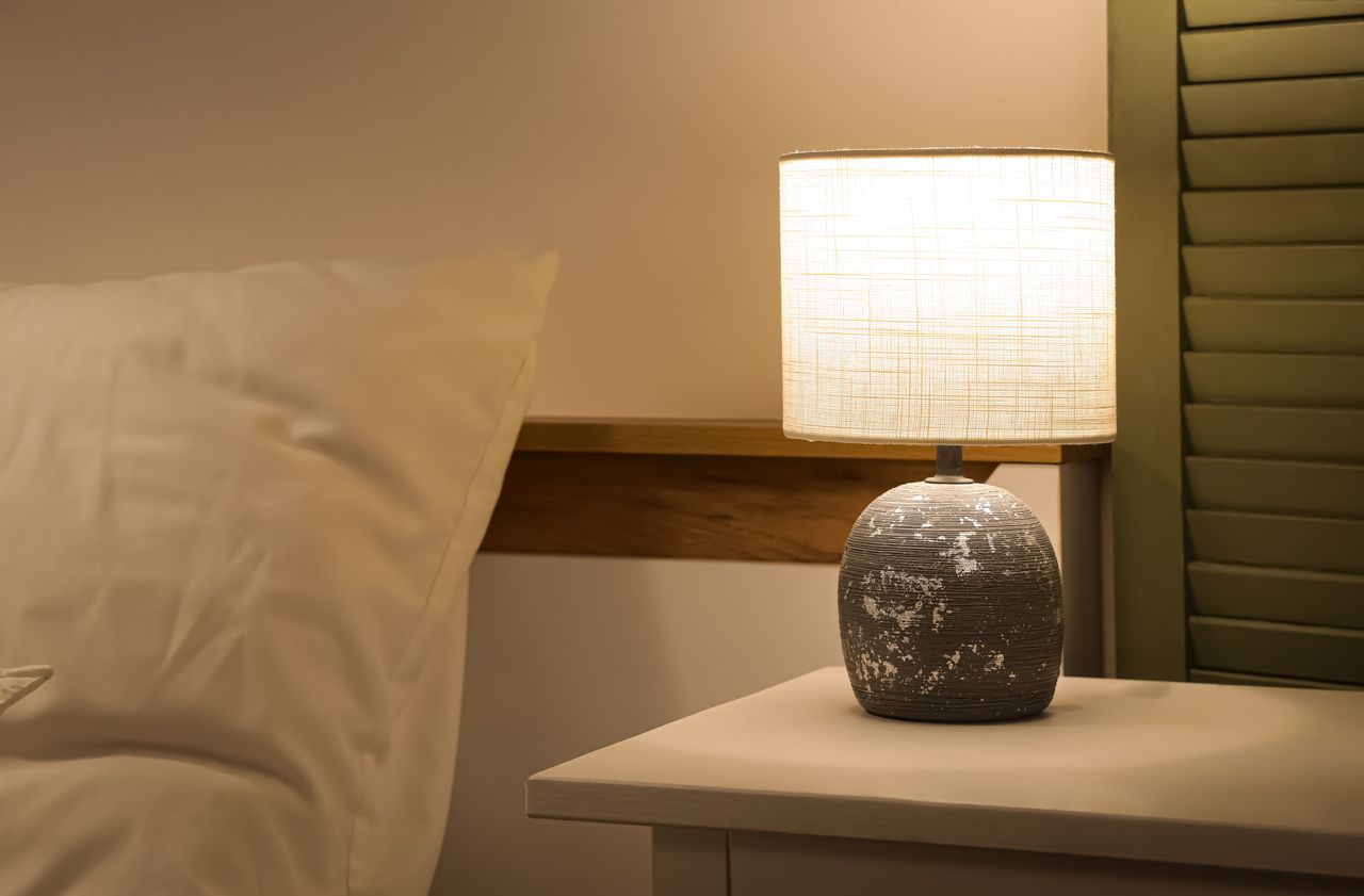 Lampe de chevet en bois flotté sur table de nuit claire, ambiance cosy et naturelle dans la chambre.