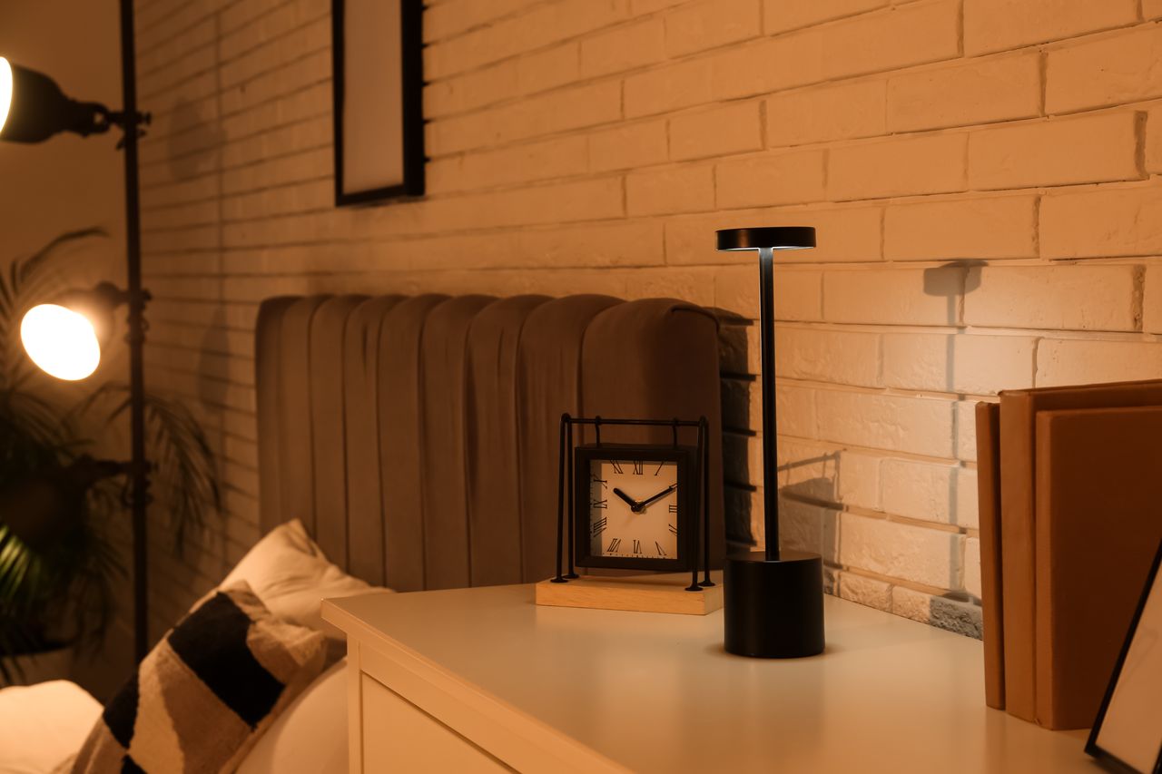 Personne fatiguée dans une chambre calme, lumière douce et réveil sur la table de nuit.