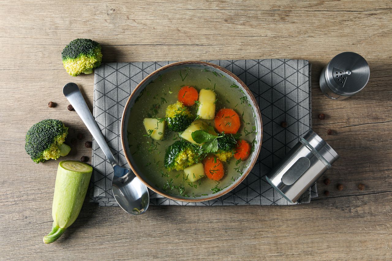 Soupe de légumes d’hiver colorée, brocoli et courgette, servie dans une cuisine chaleureuse.