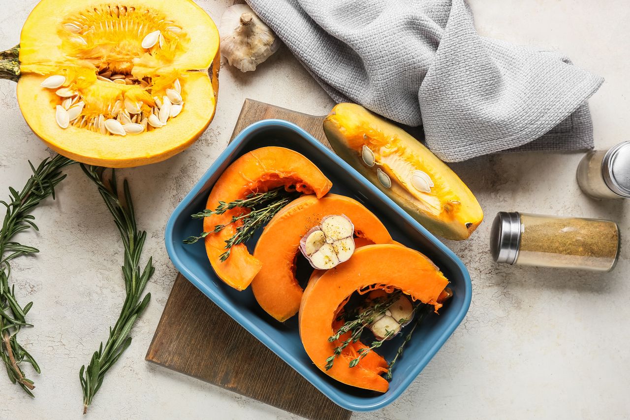 Table de cuisine avec courge, poireaux, carottes, lentilles, quinoa et bocaux de repas préparés sains.