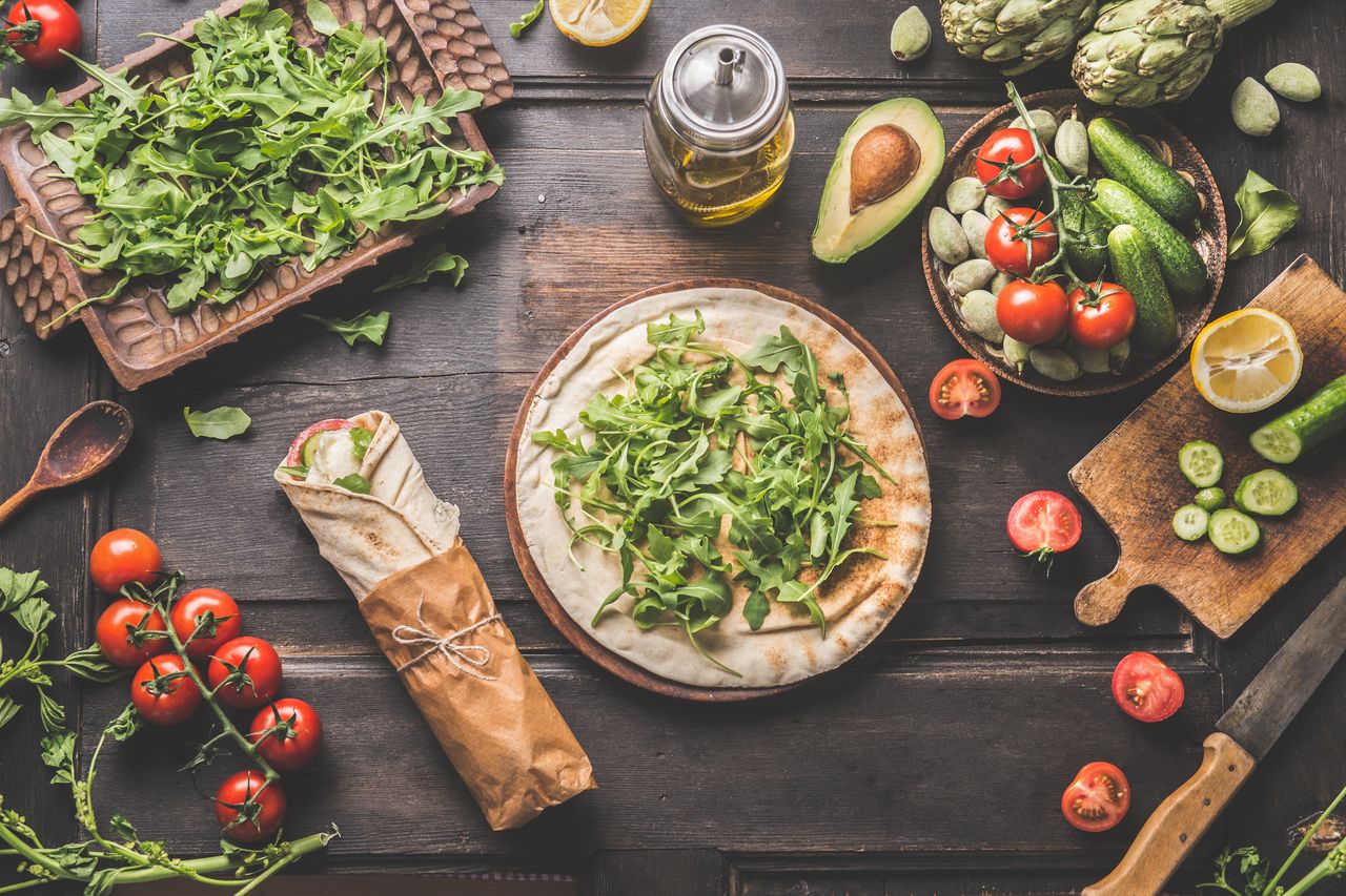 Table d’été avec salades colorées, tartare de légumes et wraps végétariens sur table en bois.