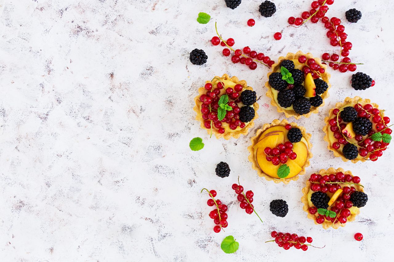 Trois tartes d’été aux fruits de saison sur table claire, avec moule à tarte, rouleau et fruits frais