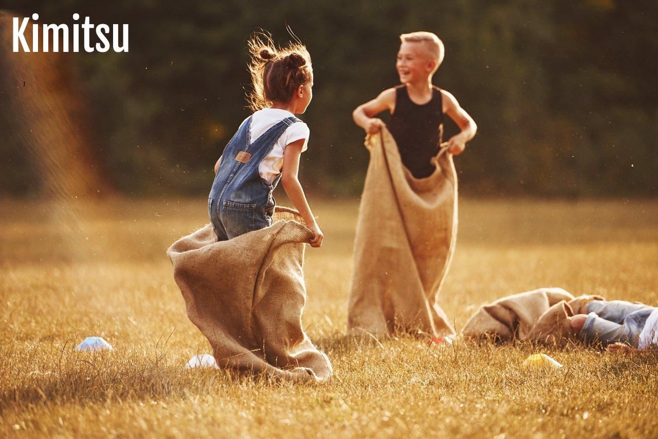 Une famille s’amusant à une course en sac lors d’un pique-nique ensoleillé dans un parc, pour un moment convivial.