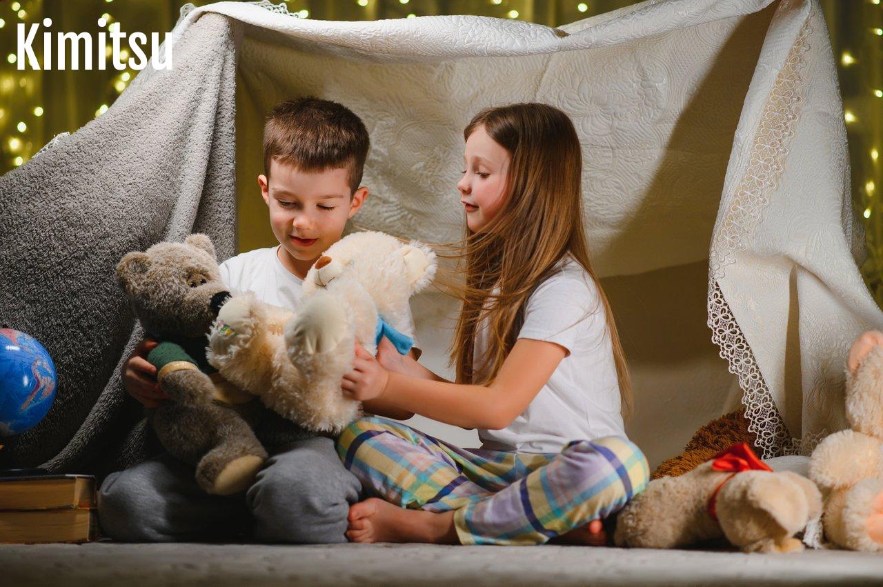 Enfants construisant une cabane intérieure avec couvertures et cartons pour un moment de jeu créatif.