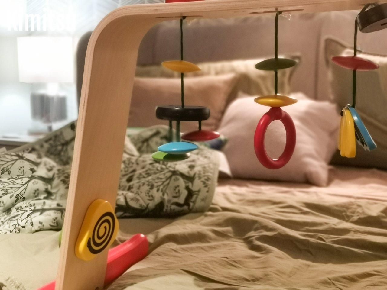 Mobile musical en matériaux naturels suspendu près d’une fenêtre, avec éléments en bois, feutrine et clochettes.